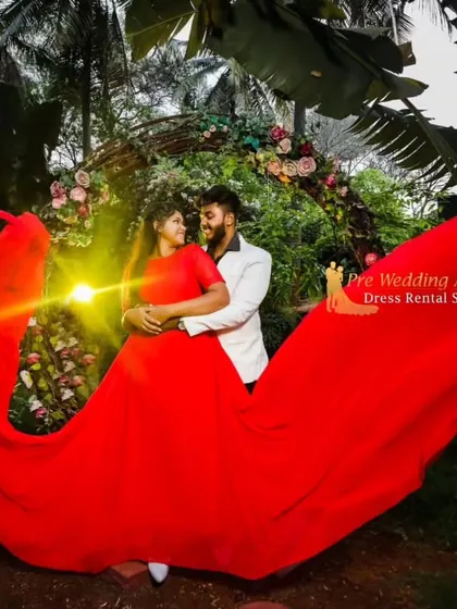 A romantic night shot of a couple surrounded by the flowing fabric of a red trail gown. The warm light creates an intimate and magical atmosphere.