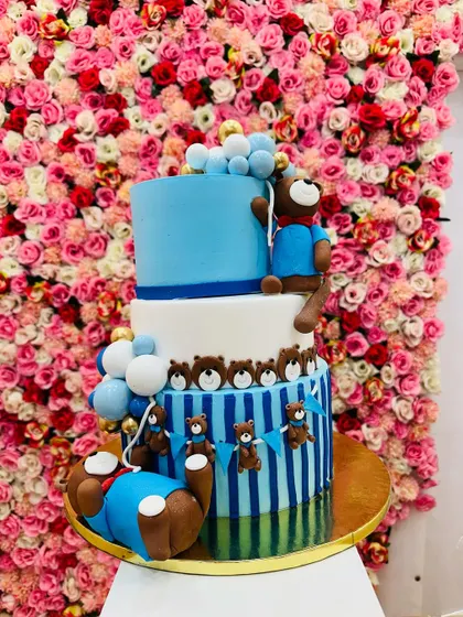 An adorable three-tiered teddy bear cake. This design features cute bears, balloons, and a striped pattern, making it perfect for a baby shower or first birthday.