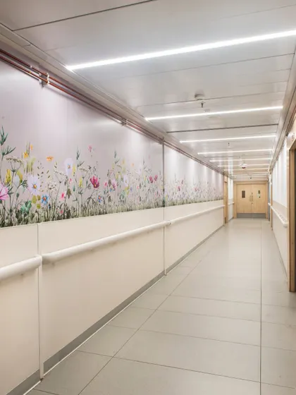 We use art and color to transform sterile corridors into therapeutic pathways. This hallway features a wall mural of wildflowers, bringing a touch of nature indoors and creating a positive distraction for patients and staff.
