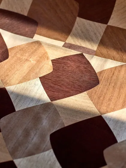 A close-up of the checkerboard wood marquetry, showing how the light catches the different grains and tones of the wood. This design is a perfect blend of natural beauty and geometric precision.