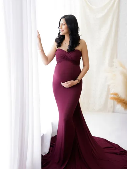 A quiet moment of anticipation. This mama-to-be looks out the window, her elegant burgundy gown and the soft natural light creating a beautiful, pensive portrait.