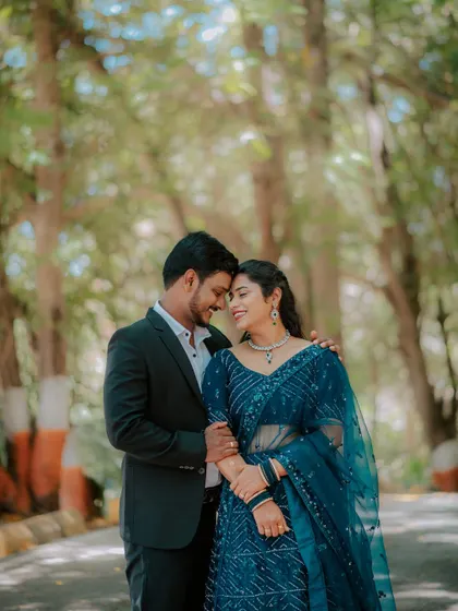 An intimate portrait of a couple under a canopy of trees.