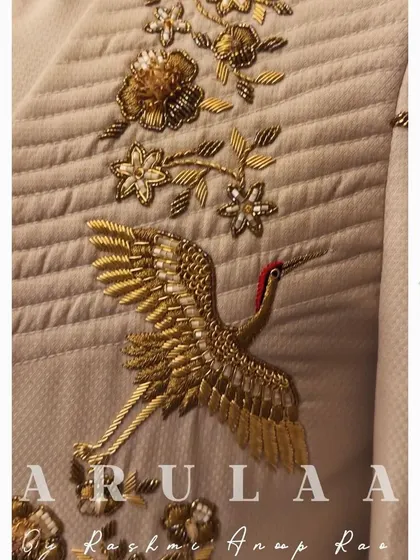 A close-up of the stunning hand-embroidered crane on the beige jacket. Every stitch is carefully placed to bring the design to life.