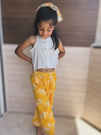 Sunshine in an outfit! This set pairs a simple white crop top with vibrant yellow floral pants. It's a cheerful and breezy combination for warm days.