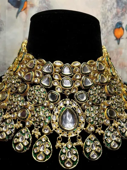 A close-up of a heavy bridal Kundan choker. The sheer density of the uncut stones and the green enamel work make this a truly extravagant piece.