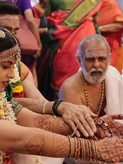 A close-up of the bride's hands during a ritual, showing the rich, dark stain of her bridal mehendi.