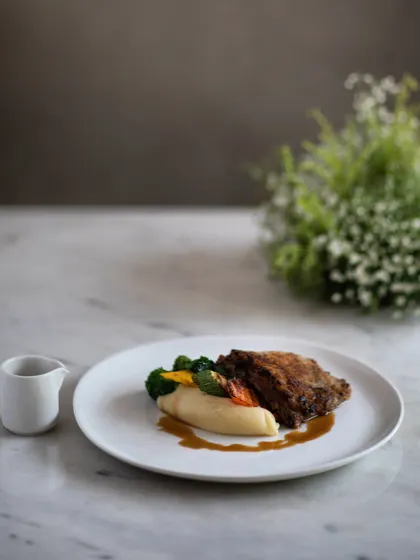 A refined and delicate main course. Our Braised and Pulled Lamb Crumbed Steak features a caramelized onion and mint crust, served with creamy mashed potatoes and a savory lamb jus.