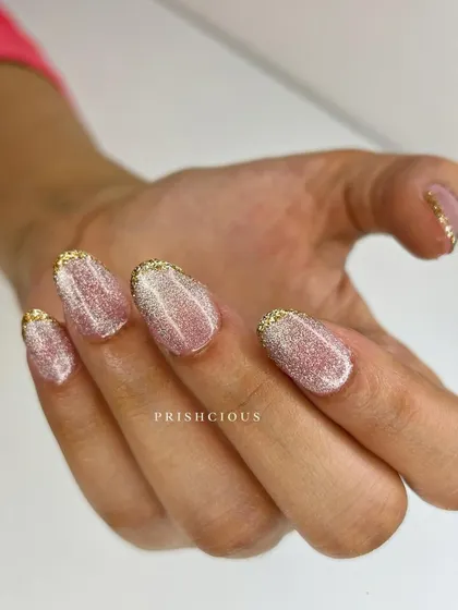When golden French elegance meets pink cat eye magic. This beautiful design combines a glittery gold French tip with a shimmery pink cat eye base.