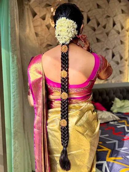 A classic South Indian bridal hairstyle featuring a long braid decorated with gold accessories and fresh jasmine flowers (gajra).