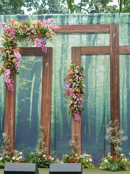 A unique photobooth with a forest-print backdrop and rustic wooden frames adorned with beautiful orchids and wildflowers.