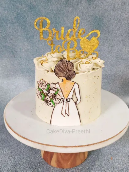 A simple and elegant cake for a bride-to-be. The design features a hand-painted illustration on the side of the cake, topped with delicate buttercream swirls.