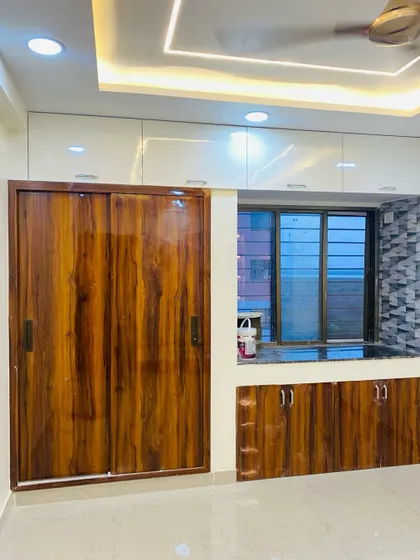 This bedroom unit features a high-gloss wooden sliding wardrobe next to a window seating area with storage cabinets below.