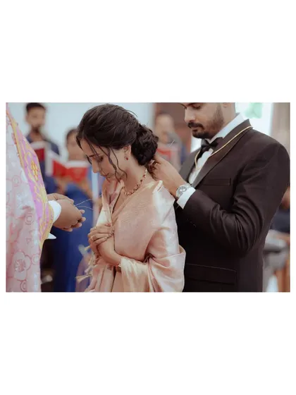 A sacred moment during a Christian wedding ceremony, as the groom places the 'minnu' (thali) around the bride's neck, symbolizing their union.