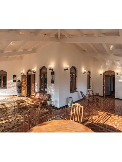 The restored veranda, where sunlight plays across the original geometric tile flooring. We focused on reviving these transitional spaces to create a seamless connection between the historic interiors and the natural surroundings, blending colonial and vernacular influences.