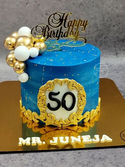 A royal blue and gold cake for a 50th birthday. The ornate gold frame and balloon accents give this cake a regal and celebratory feel.