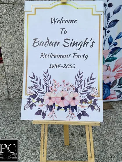 A welcome sign for the retirement party. The elegant design with a gold frame and floral motifs provides a warm and formal welcome to all the guests attending the celebration.