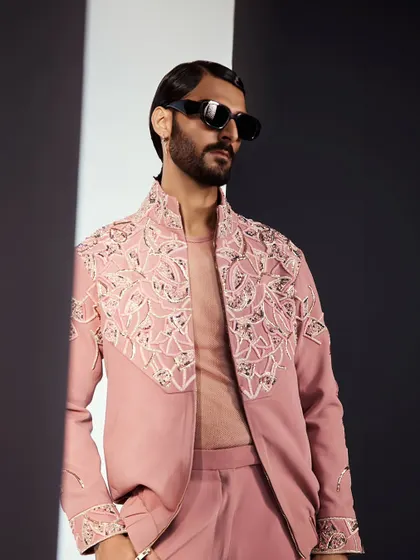 A detailed shot of the dusty rose bomber jacket. The embroidery is dense and textural, creating a rich pattern across the yoke and shoulders. It is a perfect piece for a summer event.