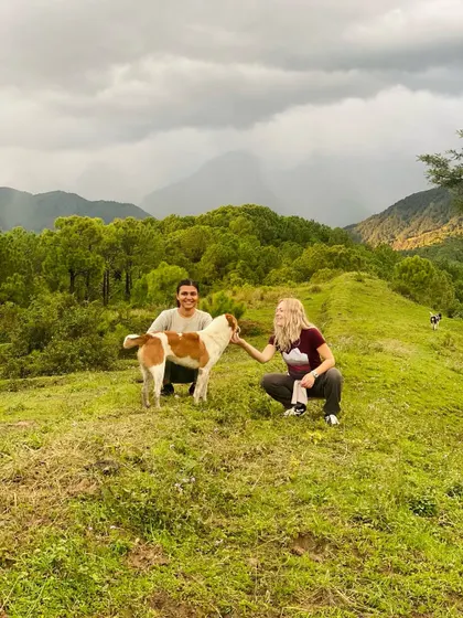 Even our four-legged friends join in the spirit of connection and joy. Two participants share a moment with a friendly local dog on a hillside in Palampur.