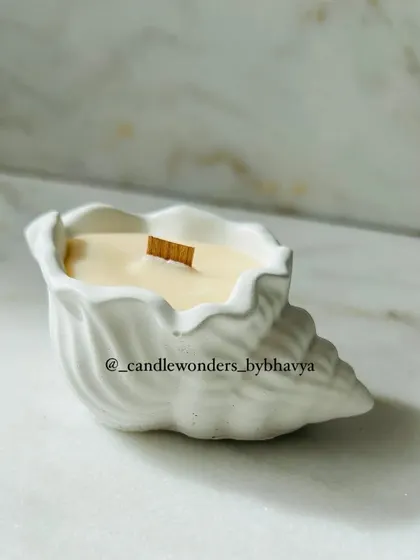 A simple and elegant sea shell candle with a wooden wick. This is a great option for a beach-themed wedding or event.