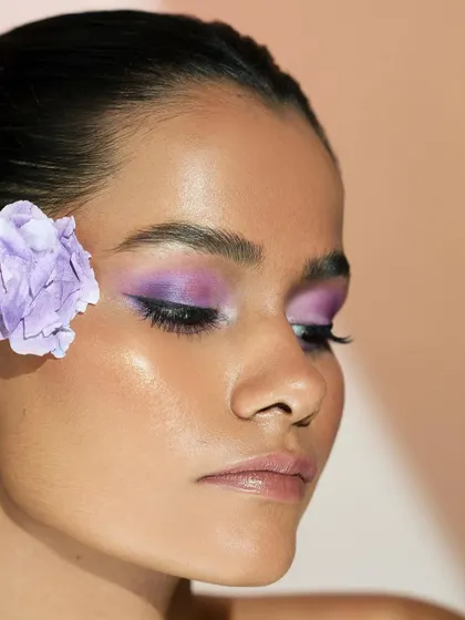 A side profile showing the seamless blend of the purple eyeshadow and the glowing skin.