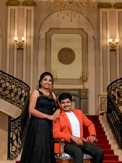 An elegant and formal pre-wedding portrait. The client's shimmering black gown and her partner's bright orange blazer create a sophisticated and modern look.