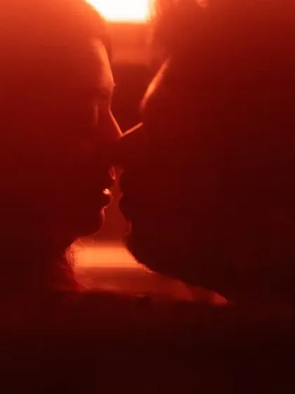 An intensely close-up silhouette in a deep red hue. This abstract and passionate shot focuses on the proximity and connection between the couple, suggesting a deep, unspoken bond.