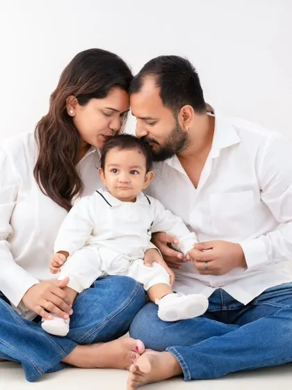 A moment of quiet intimacy. In a simple setting of white shirts and jeans, this family shares a tender forehead kiss, a beautiful, unposed expression of their bond.