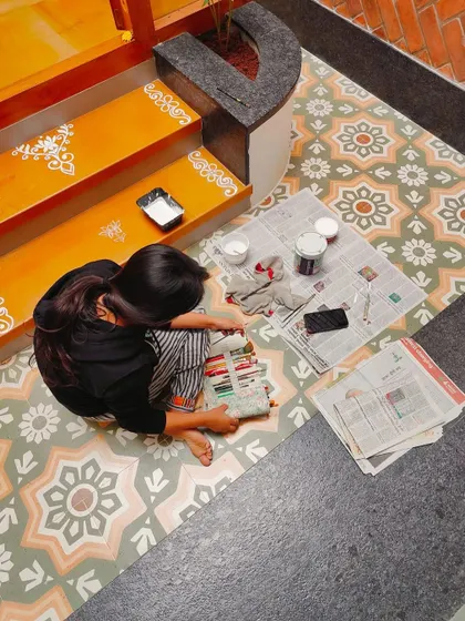 The workspace for the Alpona project, with my paints and tools ready. This kind of detailed floor painting is a unique way to customize a home.