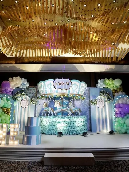 The main stage of the carnival party, featuring a carousel backdrop, hot air balloon props, and illuminated 'ONE' letters.