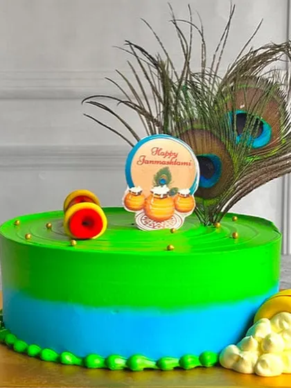 This vibrant Janmashtami cake is decorated with real peacock feathers and edible toppers. The bright green and blue colors are inspired by Lord Krishna himself.