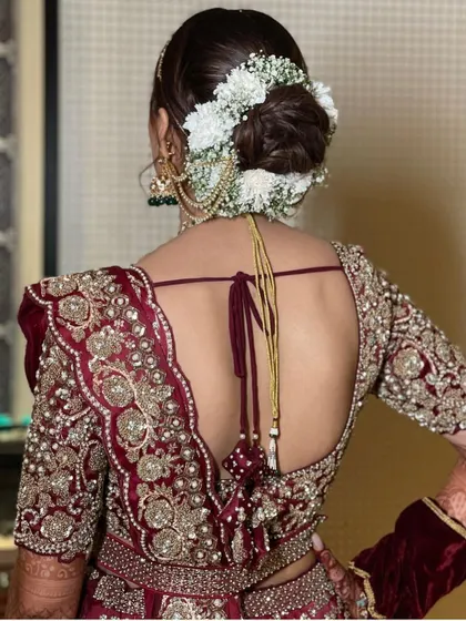 A side view of the white floral gajra bun, highlighting how it complements the bride's jewellery and the intricate embroidery of her blouse.