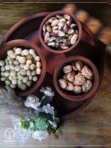 An overhead shot of my wooden dry fruit platter, showcasing a selection of premium macadamia nuts, Brazil nuts, and candied pecans. The arrangement is simple, elegant, and focuses on quality.