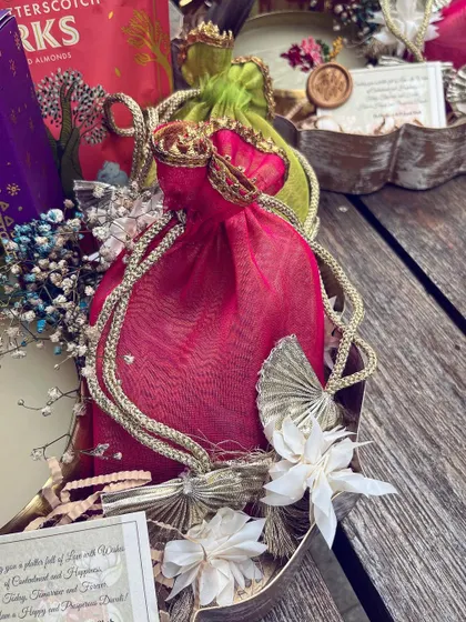 A detail shot of the vibrant potli and dried floral accents in a festive hamper.
