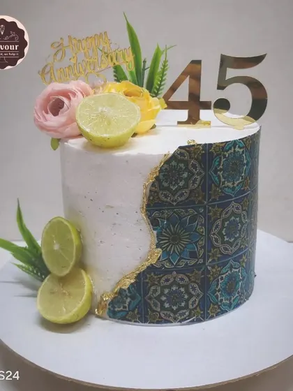 This lemon mousse cake was created for a 45th anniversary, featuring a modern design with a Moroccan tile print. The fresh lemon slices on top hint at the zesty and refreshing flavor inside.