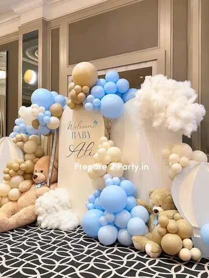 A close-up of an elegant welcome baby decoration. This angle highlights the soft textures of the cloud props and the gentle color combination of light blue, beige, and white balloons.