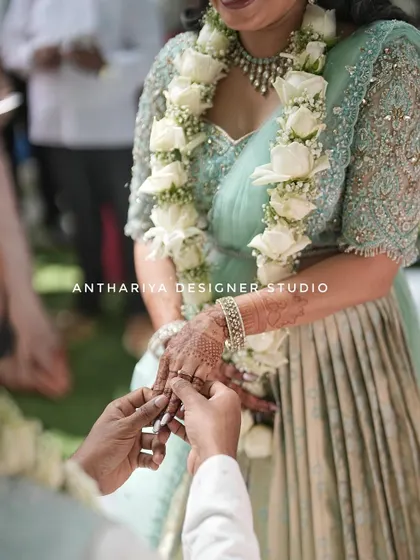The ring exchange, a close-up showing the intricate henna and the detailed embroidery on the blouse sleeve.
