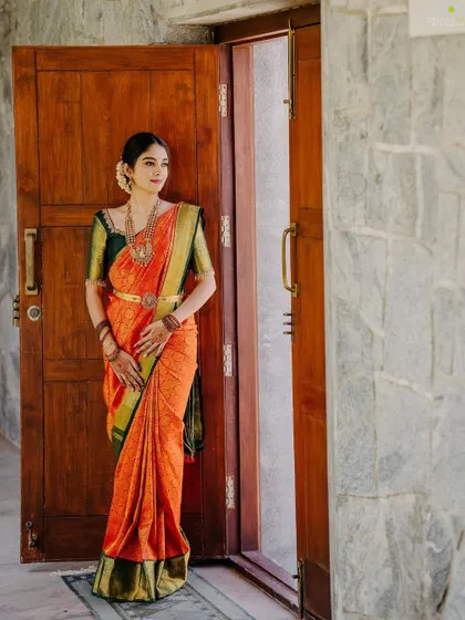 A full-length view of the client in her orange and green Kanjeevaram saree, paired with our custom green blouse.