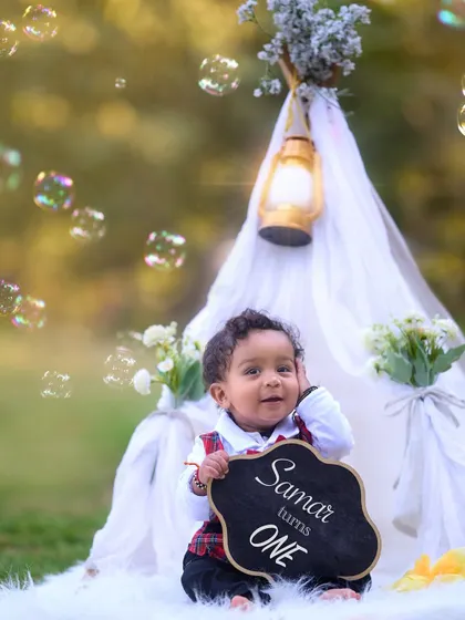 Announcing his first birthday with a smile. Surrounded by bubbles and a cozy teepee setup, this little one is all set for his milestone photoshoot.