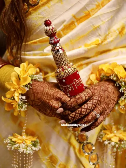 A candid moment from a haldi ceremony, with the bride's beautifully adorned hands. The back-hand design complements her floral jewelry perfectly.