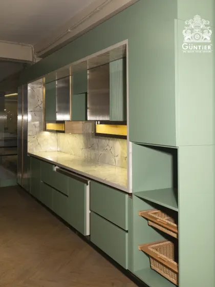 We love playing with color and texture. This modular kitchen features a unique combination of sage green cabinets, a reflective metallic finish, and warm wood accents for a truly bespoke look.