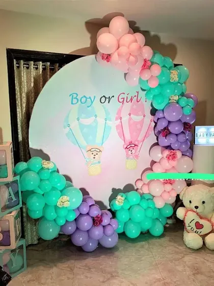 A 'Boy or Girl' gender reveal party with a hot air balloon themed backdrop and a colorful balloon arch.