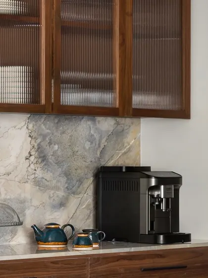 A detail from the West Coast Residence kitchen, where fluted glass cabinet doors and a beautiful marble backsplash add texture and refinement. The space is designed to be both a functional work area and a beautiful part of the home.