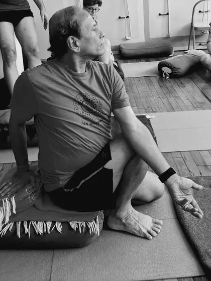 A seated twist, Marichyasana III, performed on a blanket to elevate the hips and facilitate a deeper twist.