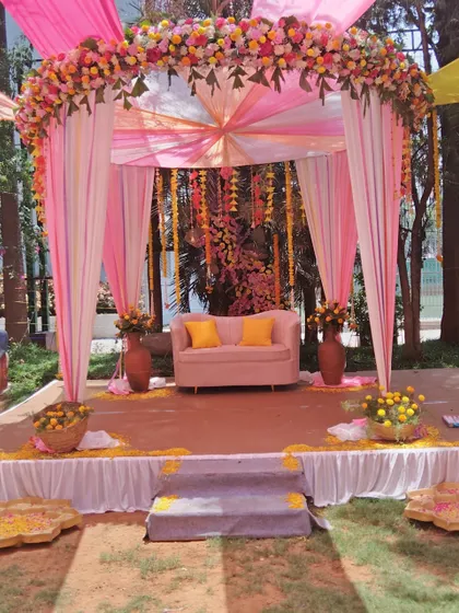 A colorful outdoor stage with pink and yellow drapes, perfect for a Mehendi or Haldi ceremony.