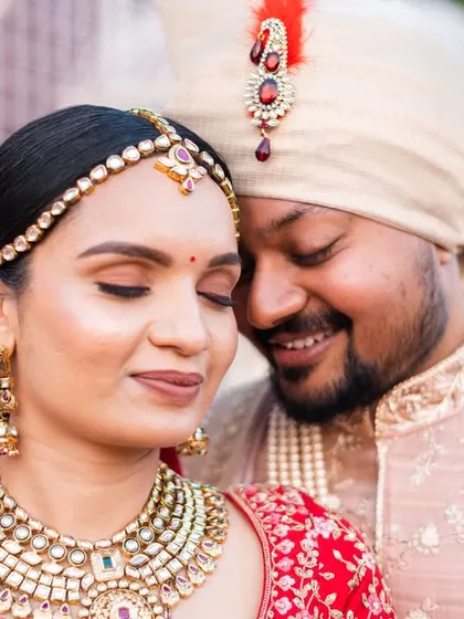 A close-up portrait that beautifully captures the intricate details of the bride's jewelry and makeup, and the couple's gentle affection.