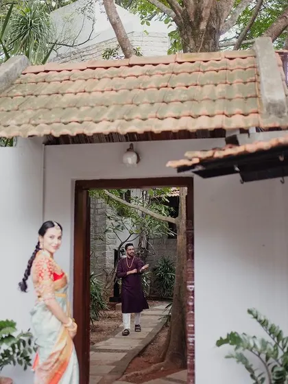 A bride looks back over her shoulder, framed by a white doorway and garden path, a lovely, candid-style portrait.