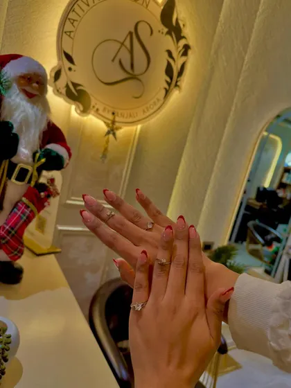 Getting into the festive spirit with these red-tipped French nails. They offer a classic look with a pop of holiday color, pictured here in our decorated salon.