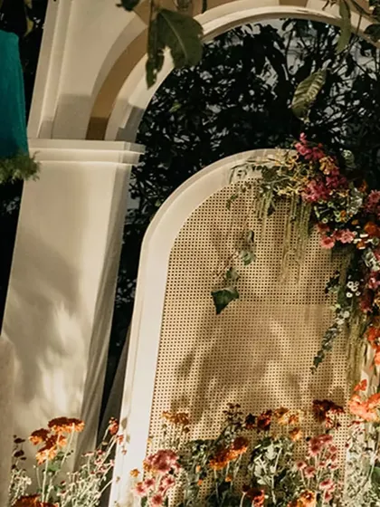 A close-up of the floral decor on the mandap arches. We used a mix of bright red bougainvillea and other colorful blooms, with a rattan screen adding a touch of texture.