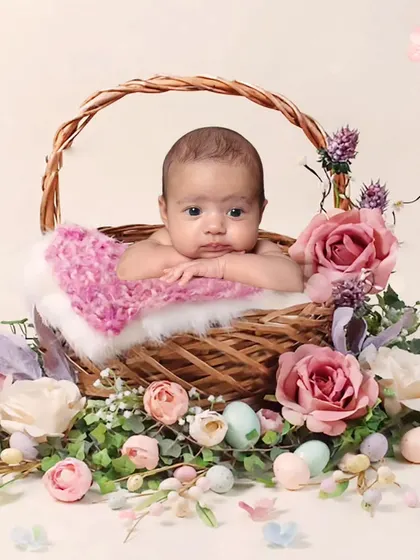 A sweet baby portrait in a wicker basket surrounded by pastel-colored flowers and Easter eggs. This is a perfect setup for a spring-themed photoshoot.