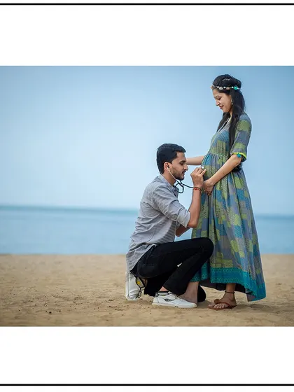 The dad-to-be playfully uses a stethoscope on the beach, a cute and memorable moment from their maternity session.